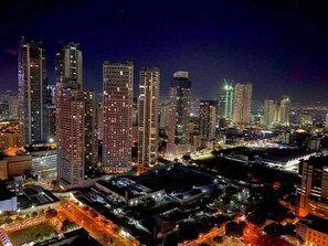 A nighttime cityscape with high-rise buildings and illuminated streets. - Stylish City Escape in Mandaluyong - Central Condo Living (Mandaluyong)