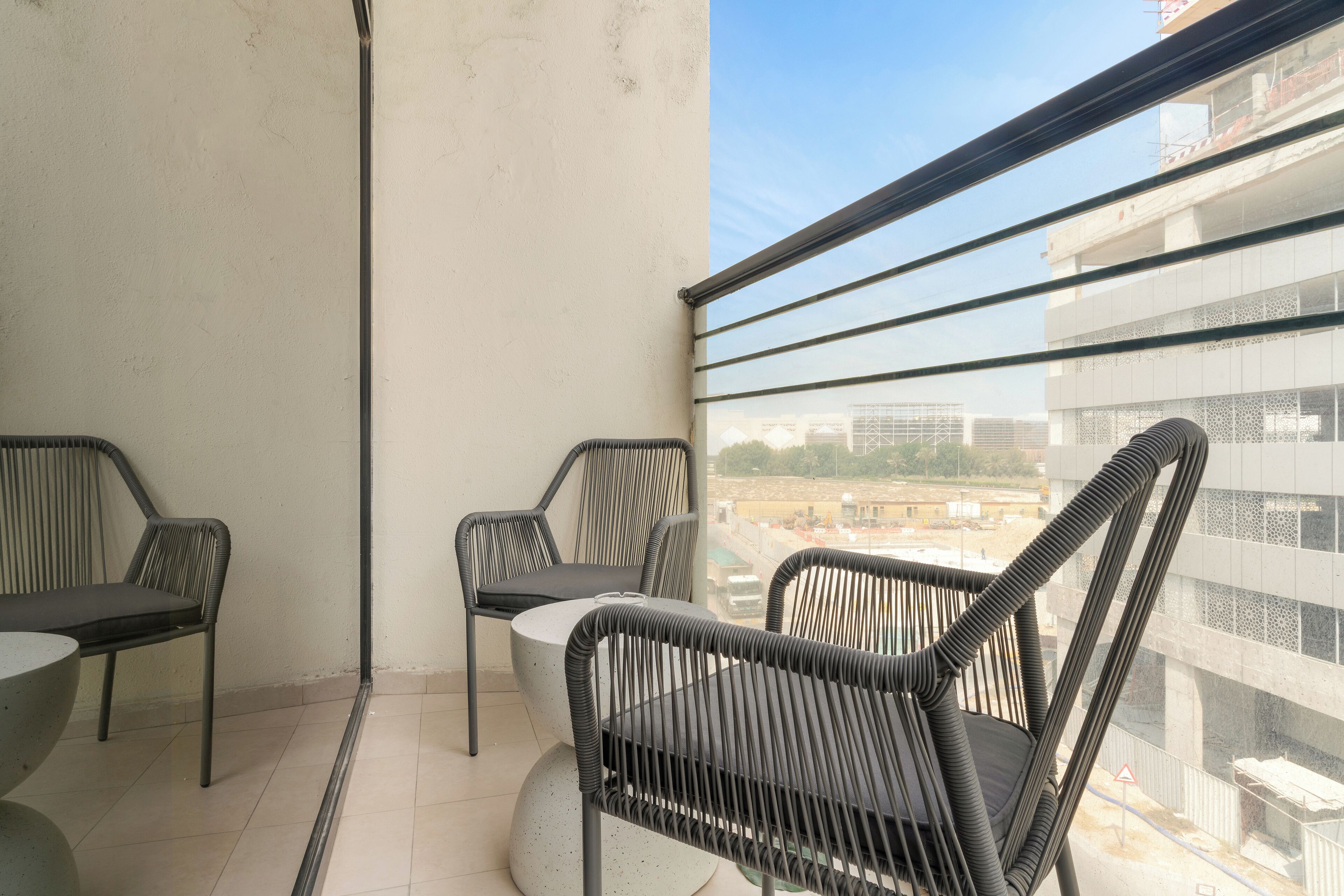 A balcony with two chairs and a table, overlooking a cityscape.
