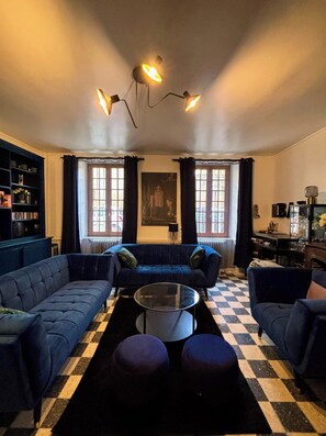 A living room with a blue sofa set, a glass coffee table, and a checkered floor. - Gîte Montana 3 pers. plein center Mirepoix - Terrace, garden, barbecue (Mirepoix)