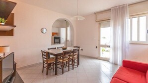 A modern living room with a dining area, a red sofa, and a kitchen visible through an archway. - Tulip house with sea view in Torre Vado (Torre Vado)