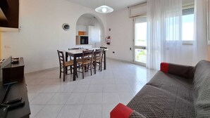 A modern living room with a sofa, a dining area with chairs and a table, and a kitchen in the background. - Tulip house with sea view in Torre Vado (Torre Vado)