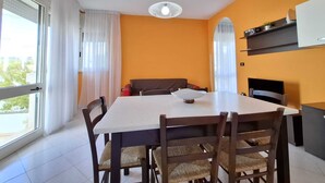 A dining area with a table and chairs, a ceiling fan, and a view through a window with curtains. - Tulip house with sea view in Torre Vado (Torre Vado)