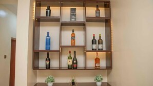 A wooden liquor cabinet with shelves holding various bottles of liquor. - Tourmaline- Cozy 2-bedroom apartment in serene Lagos with AC (Lagos)