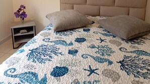 A bedroom with a bed, a nightstand, a vase with flowers, and a painting on the wall. - At Lia and Danny's (Rieux-Minervois)