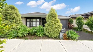 A residential house with a well-maintained garden, a driveway, and a clear blue sky. - Happy Cozy Convenient 4BR, Breezy, Near Mall, Park (Berwick)