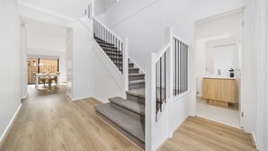 A modern interior with a staircase, wooden flooring, and a view into a dining area. - `Brand New`, Spacious, Breezy Comfy, Luxury Home ! (Berwick)