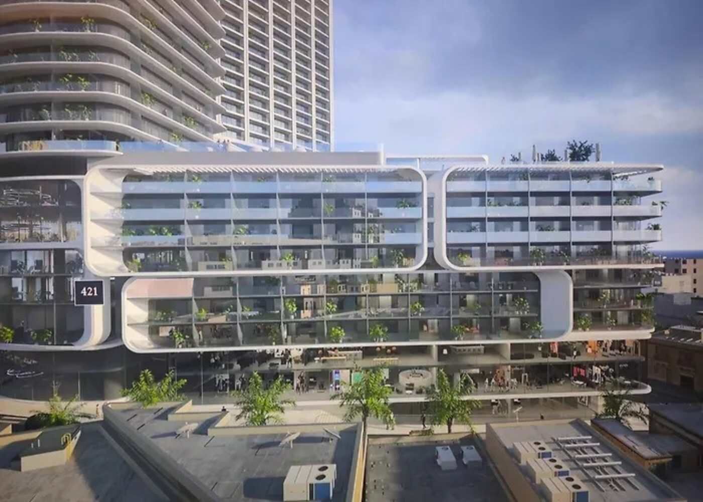A modern multi-story building with balconies, large windows, and a flat roof.