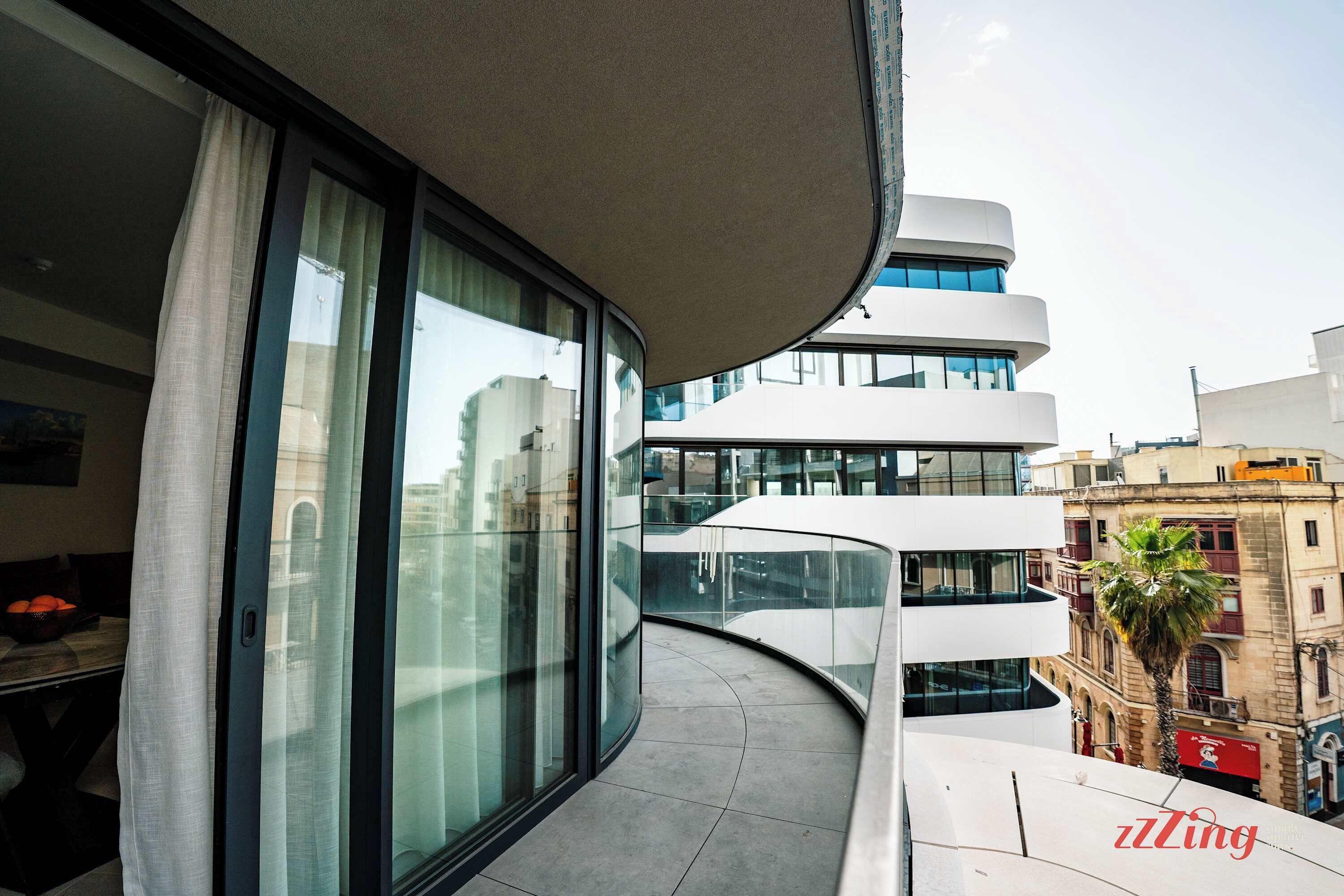 Ein modernes Gebäude mit großen Fenstern und einem geschwungenen Balkon.