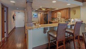 A spacious kitchen with wooden cabinets, a large island with bar stools, and a view into the adjacent dining area.