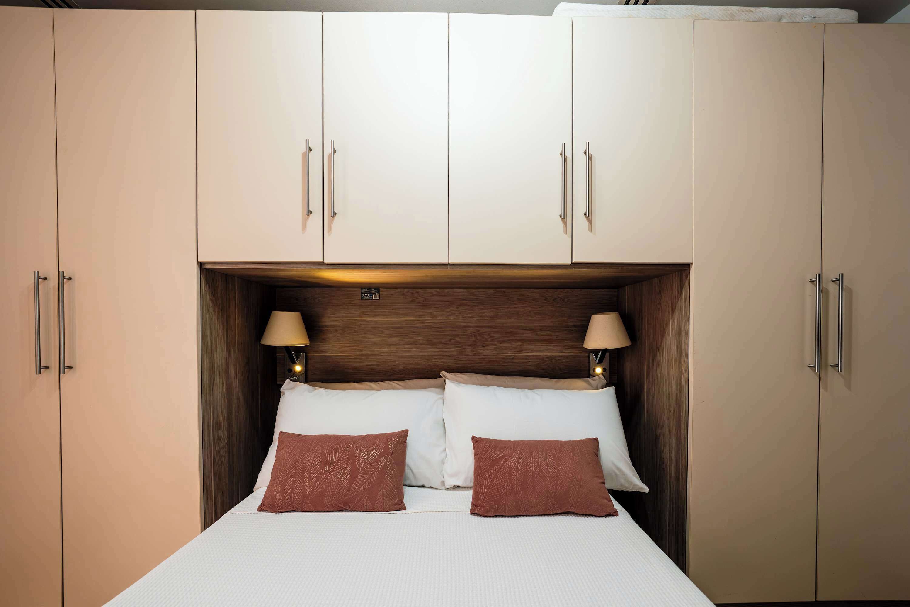 Una habitación de hotel con una cama grande, dos lámparas de noche y un cabecero de madera.