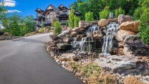 Un edificio de varios pisos con una cascada de piedra y un camino pavimentado que lo lleva a él.