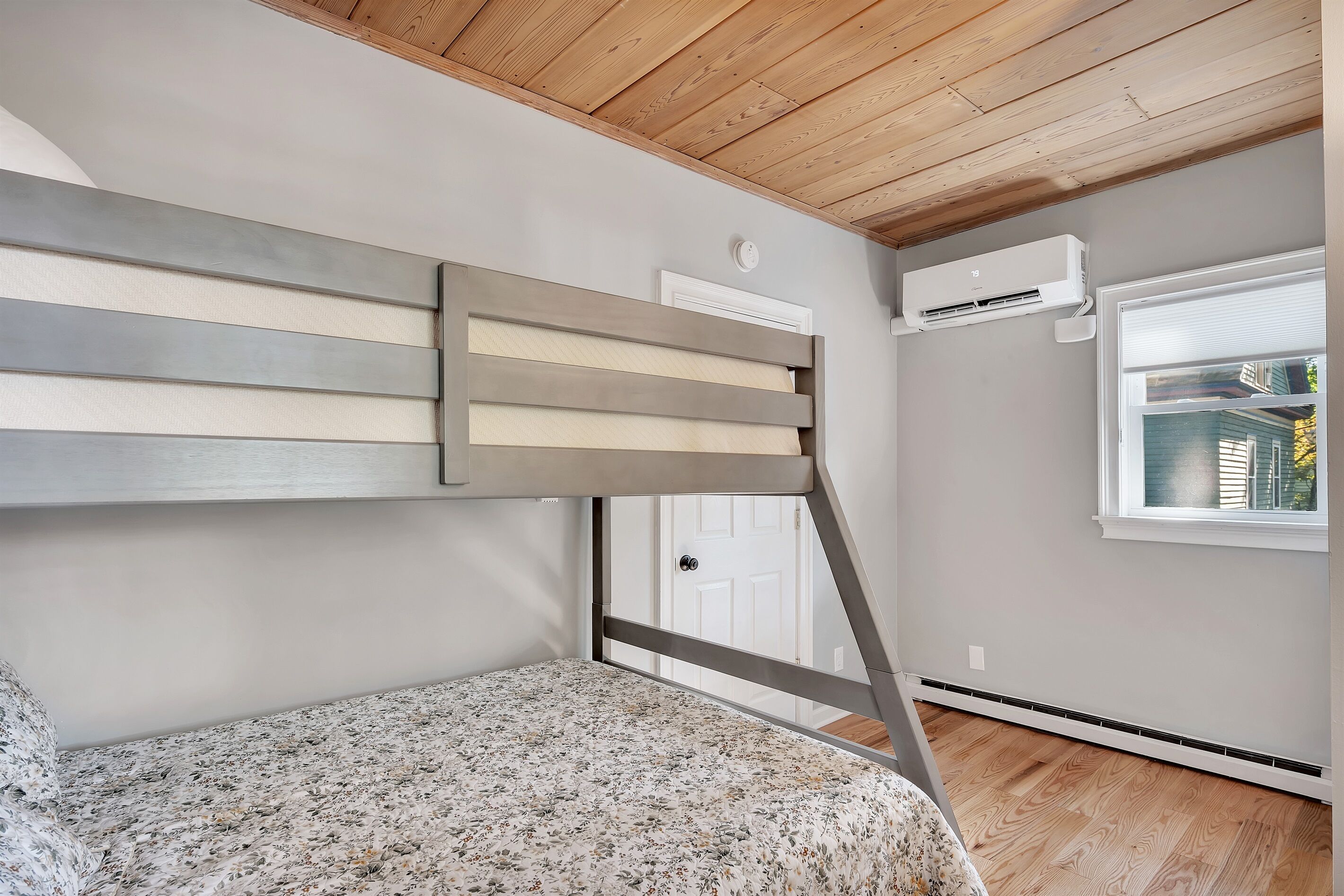 Un dormitorio con una cama litera, una ventana con persianas, un ventilador de techo y un termostato.