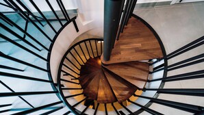 A spiral staircase with a wooden finish and black metal railings. - Msida's Most Loved Stylish Duplex Retreat (Tal-Pietà)