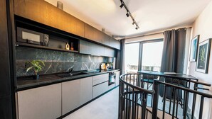 A modern kitchen with a black countertop, a built-in oven, and a window overlooking a balcony. - Msida's Most Loved Stylish Duplex Retreat (Tal-Pietà)
