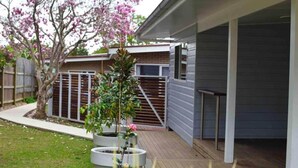 A residential backyard with a covered patio, a tree with pink blossoms, and a brick wall.