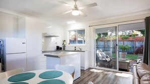 A modern kitchen with a built-in island, a dining area with a table and chairs, and a sliding glass door leading to a patio with outdoor seating.