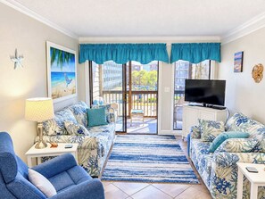 A living room with a sofa, a chair, a TV, and a view of the outside.