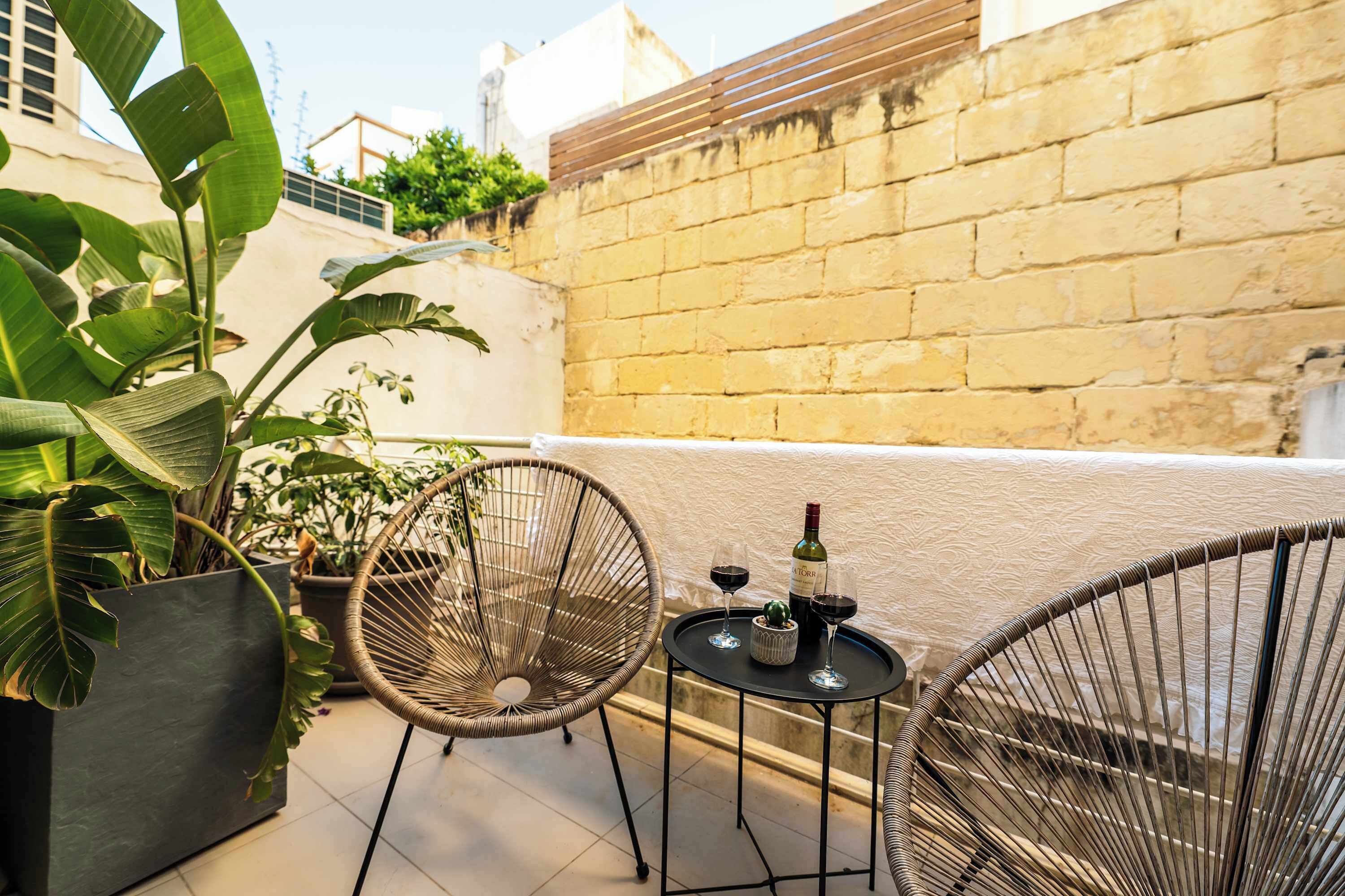 A terrace with two wicker chairs, a small round table, and a potted plant.