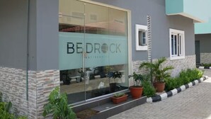 A modern building with a large glass facade, a sign reading "BEDROCK Residences," and a stone and brick exterior.