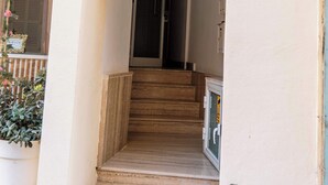 Ein Hauseingang mit einem Schild, auf dem "Two86A Residence" steht, über einer Holztreppe, die zu einer Tür führt.
