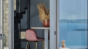 Ein modernes Interieur mit einem pinken Sessel, einer Vase mit Trockenblumen und Blick durch eine Glastür.