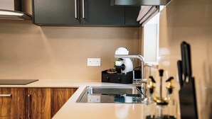 A modern kitchen with a built-in espresso machine, wooden cabinets, and a stainless steel sink.