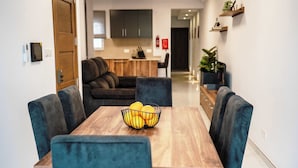 A modern dining area with a wooden table, blue upholstered chairs, and a fruit bowl.
