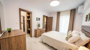 A modern bedroom with a bed, bedside tables, a wardrobe, and a bathroom visible through an open door.