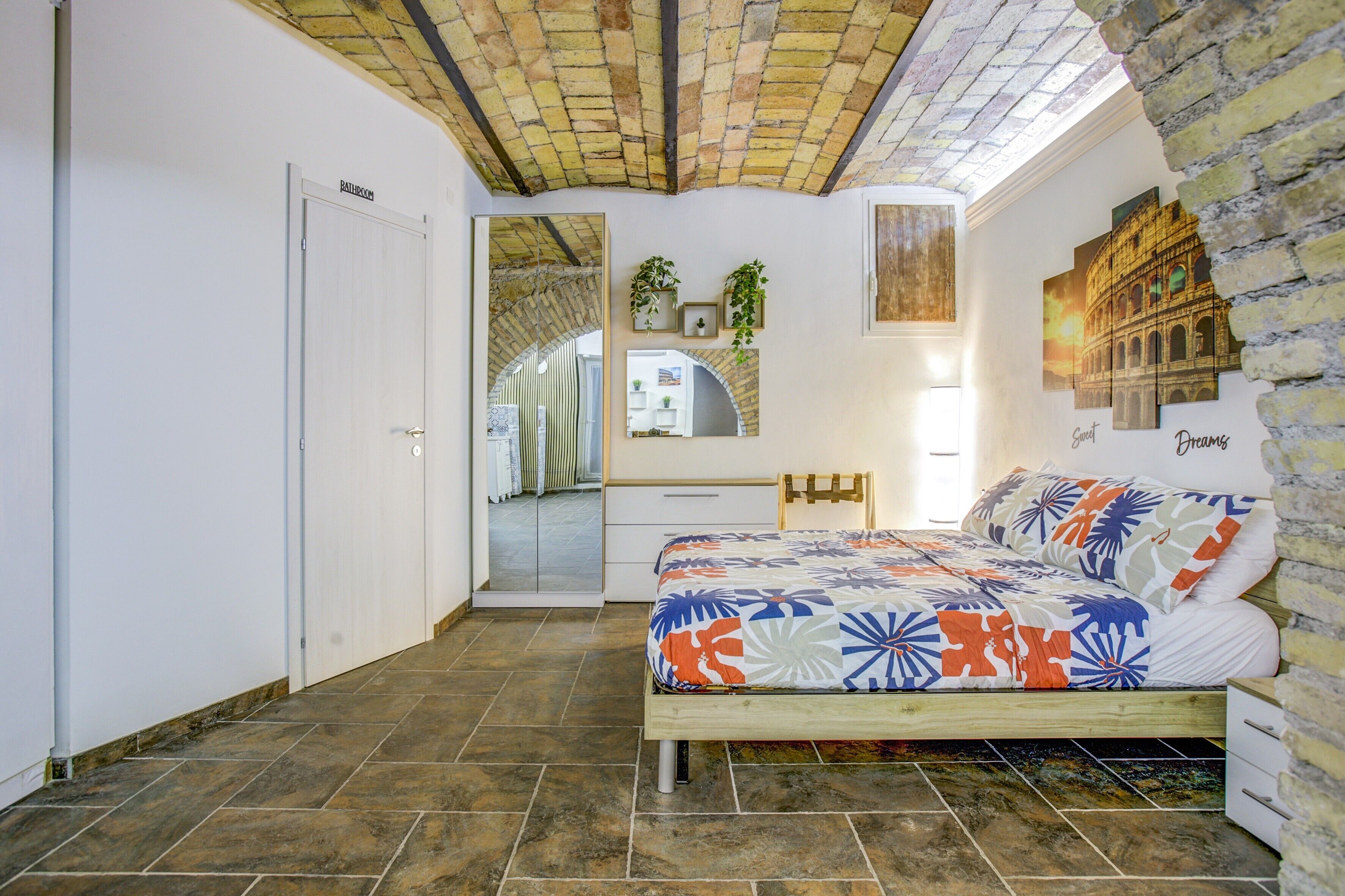 Une chambre à coucher avec un lit, un miroir, une armoire, un bureau et une porte menant à la salle de bain.