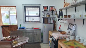 A compact kitchen with a wooden table, a refrigerator, and a window with blinds.