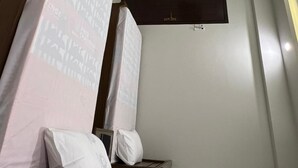 A hotel room with two beds, a flat-screen TV mounted on the wall, and a dark wooden wardrobe. - Prestige Comfort Apartments Separate Lounge With Newly Bath With Reception (Karachi)