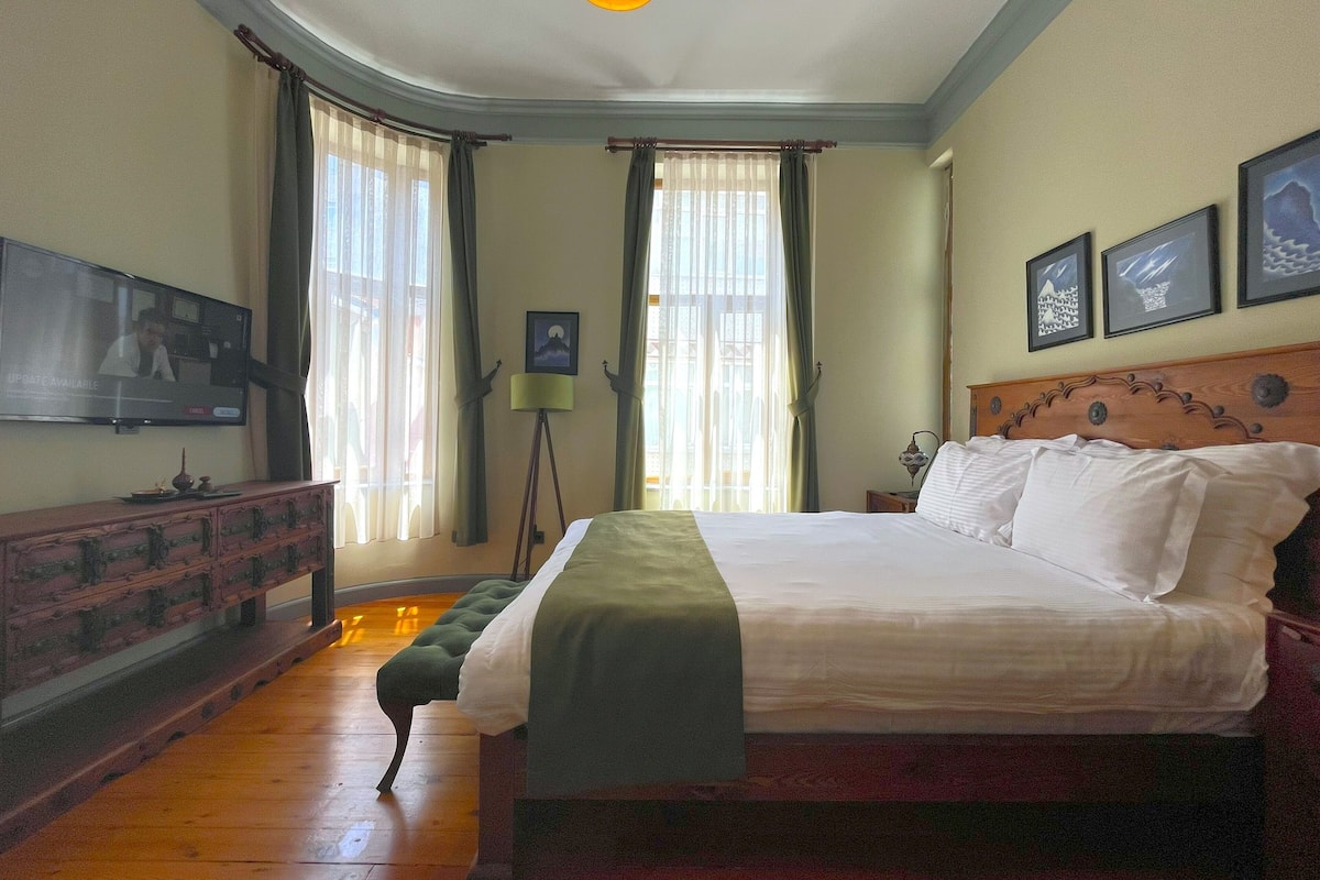A bedroom with a large bed, a television on the wall, and a floor lamp.
