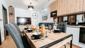 A modern kitchen with wooden cabinets, a built-in microwave, and a dining area with a wooden table set for a meal. - Holiday Home Near the Sea, air Conditioning (Ustronie Morskie)