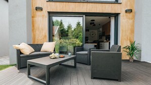An outdoor seating area with wicker furniture, a coffee table, and a potted plant. - Holiday Home Near the Sea, air Conditioning (Ustronie Morskie)