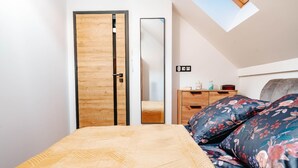 A bedroom with a bed, a wooden wardrobe, a dresser, and a mirror. - Holiday Home Near the Sea, air Conditioning (Ustronie Morskie)