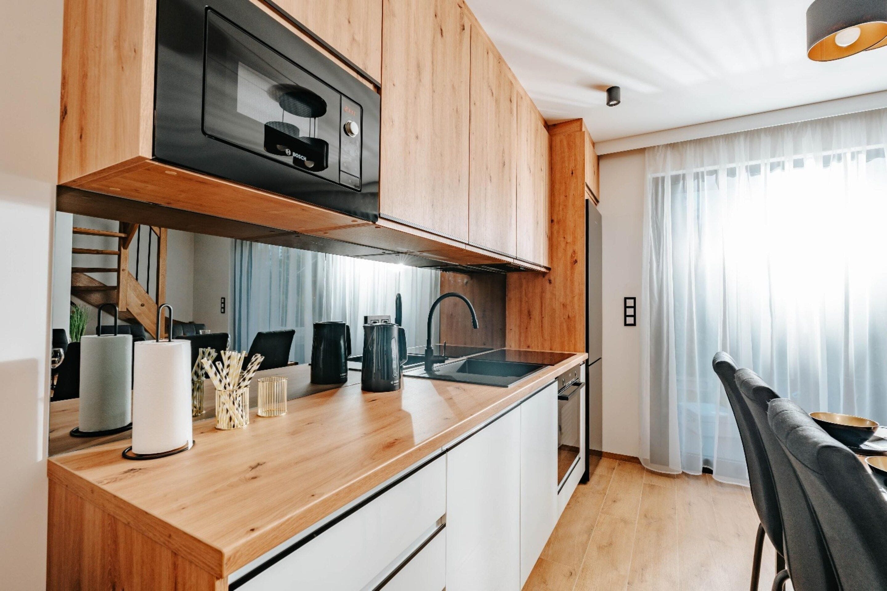 Une cuisine moderne avec des meubles en bois, un four encastré et une hotte en acier inoxydable.