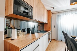 A modern kitchen with wooden cabinets, a built-in oven, and a stainless steel range hood. - Holiday Home Near the Sea, air Conditioning (Ustronie Morskie)
