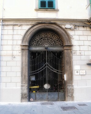 A large, ornate metal gate with intricate designs, set within a stone archway above a building entrance. - Casa Vacanze le Coccole (Napoli)