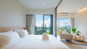 A modern hotel room with a large bed, a seating area with a view, and a balcony.