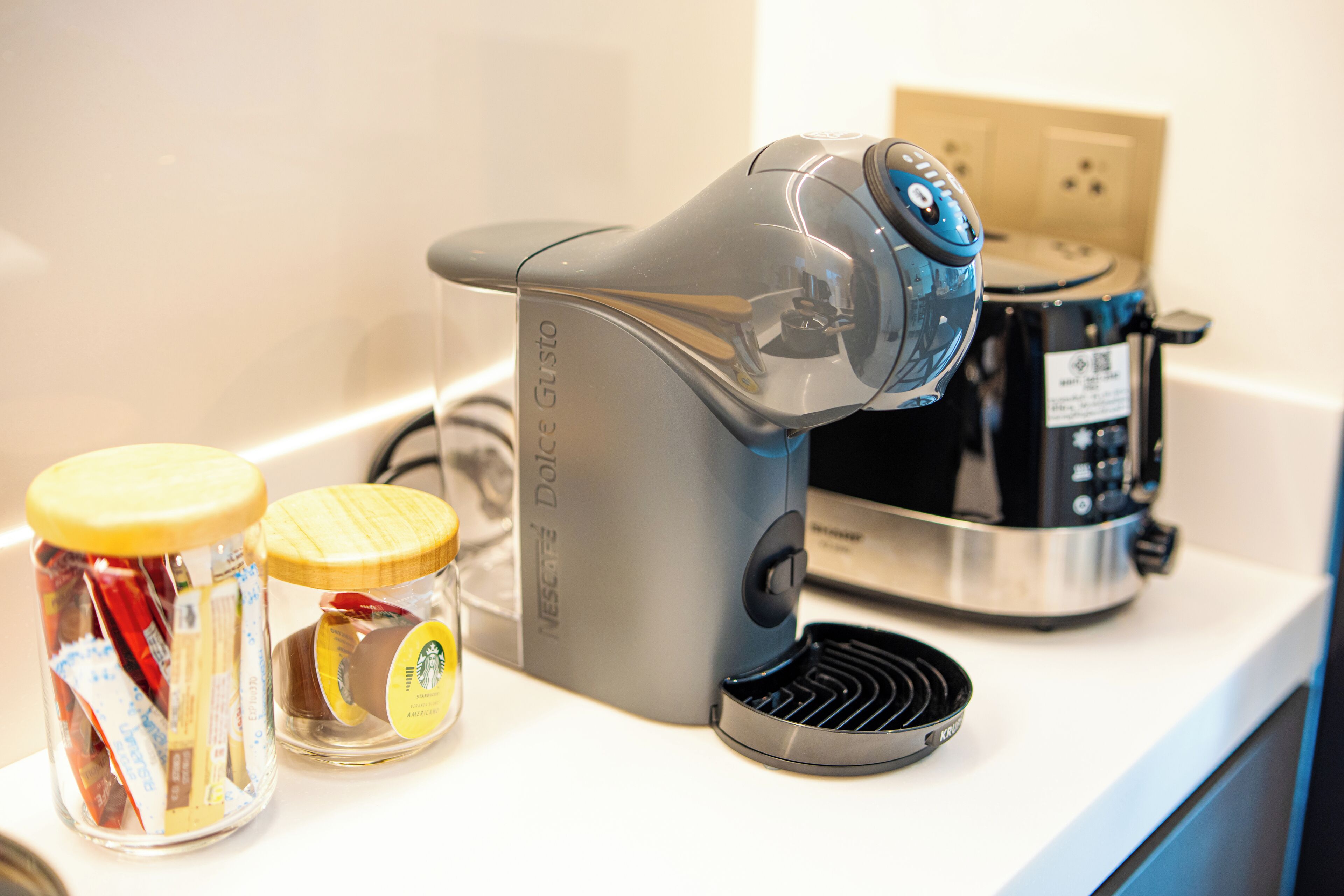 A kitchen with a coffee maker, a toaster, and two jars of spices.