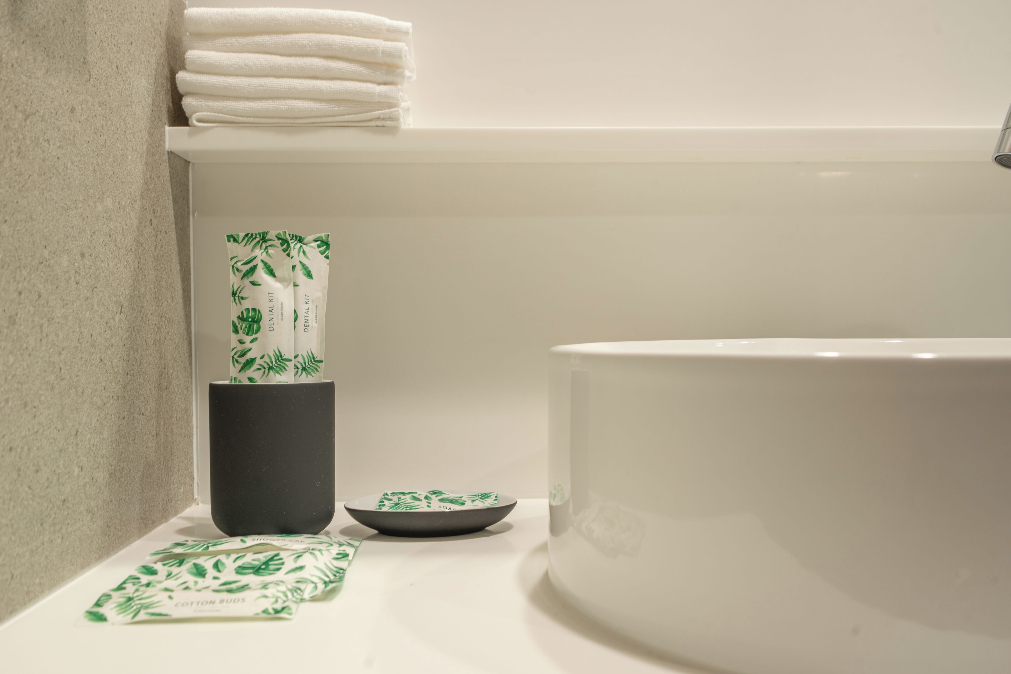 Une salle de bain avec une baignoire, une pile de serviettes blanches, un récipient noir et un petit bol.