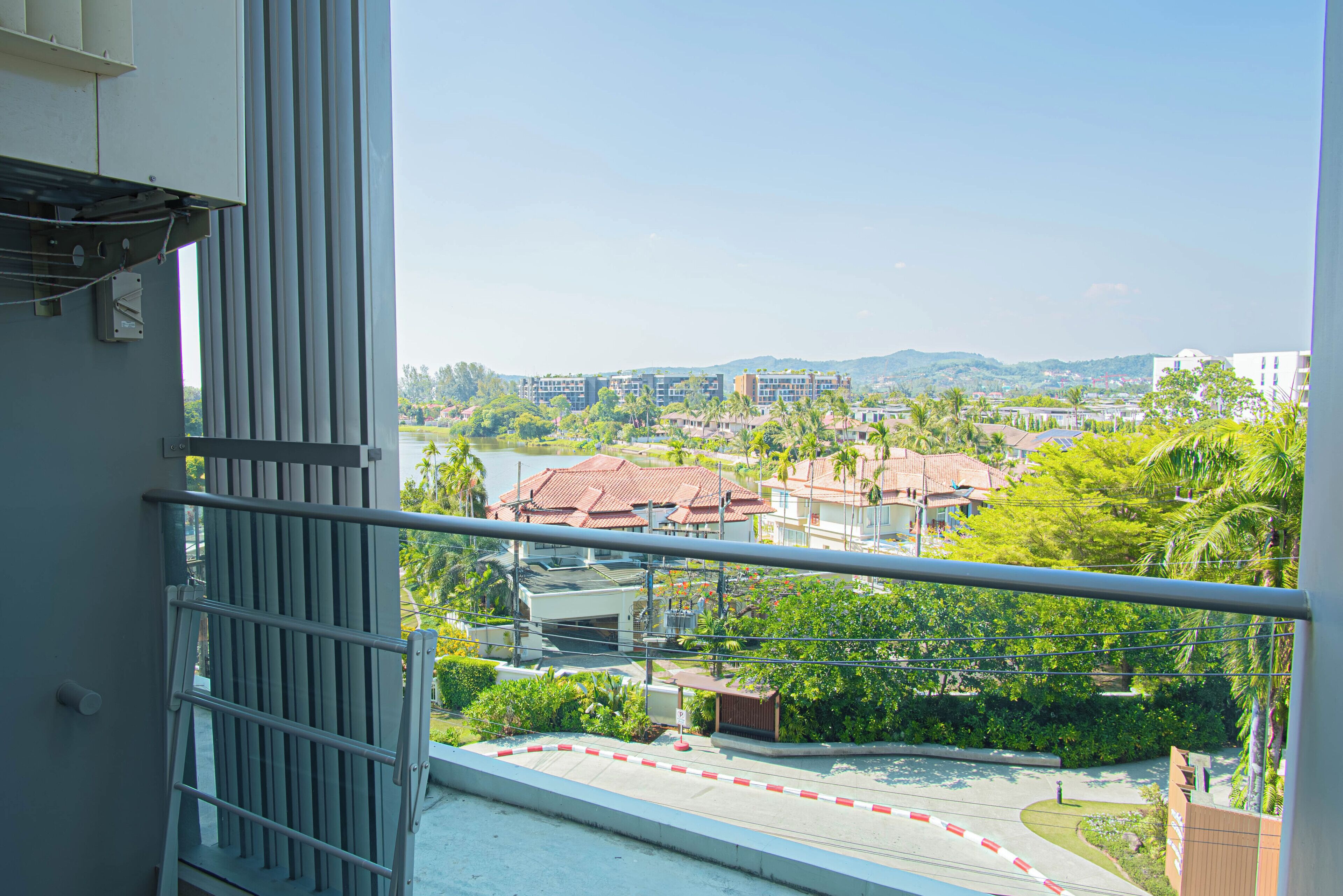 A balcony with a view of a residential area, including buildings and greenery.