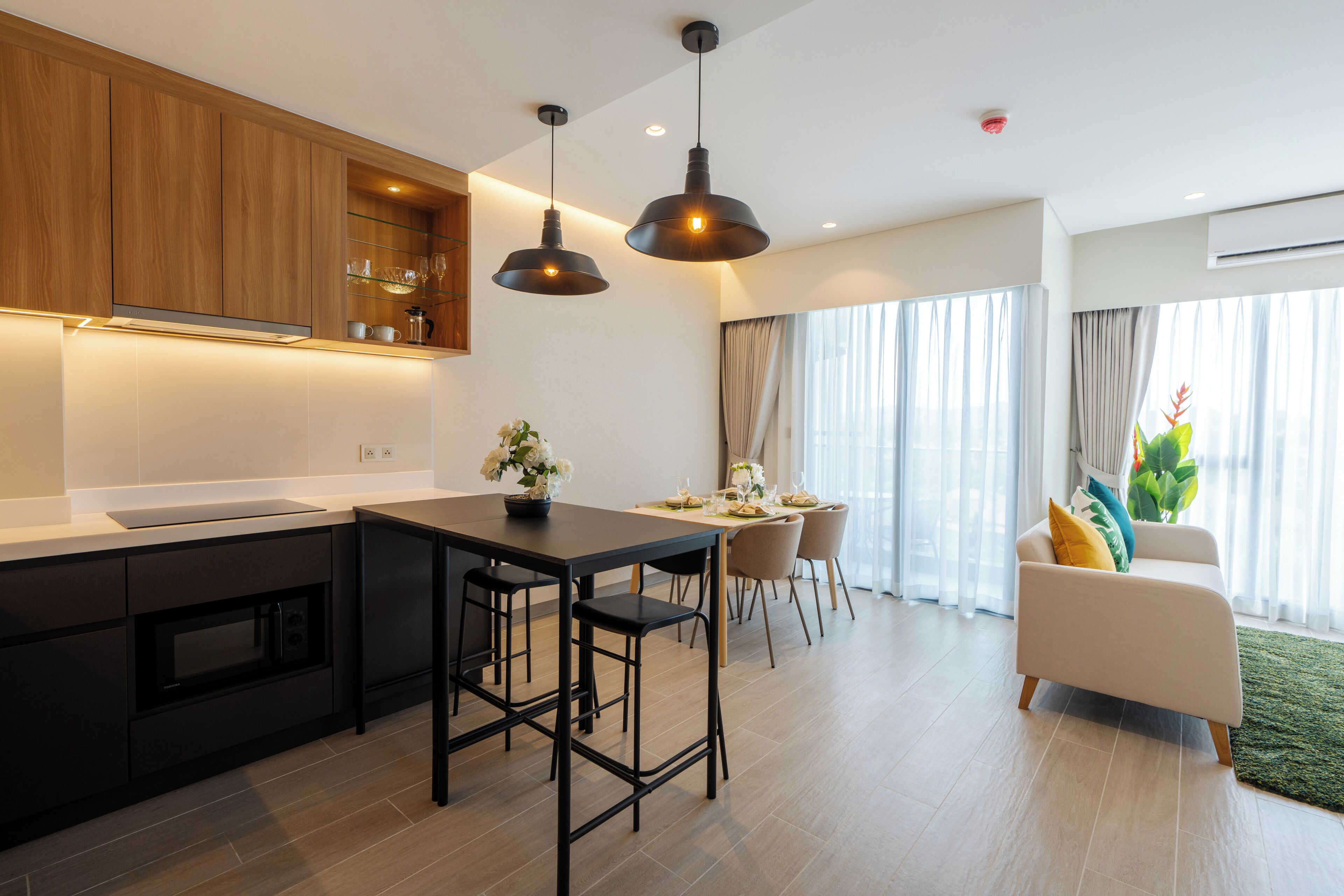 Una cocina moderna con una isla central, taburetes de bar e iluminación colgante.