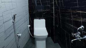 Une salle de bain moderne équipée de toilettes, d’une douchette à main et d’un robinet mural.
