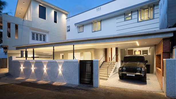 Une maison moderne à deux étages, dotée d’un garage fermé et dans lequel est garé un SUV noir.