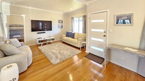 A modern living room with a sofa, a coffee table, a TV, and a door with a picture frame.
