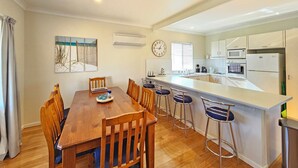 A modern kitchen with a central island, bar stools, and a dining table with chairs.