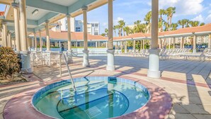 Un espace piscine doté d’un jacuzzi, de chaises longues et de palmiers.