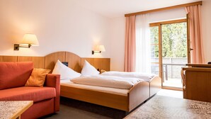 A hotel room with a bed, a sofa, a desk, and a balcony with curtains. -  Sleep Well 24 (Spittal an der Drau)