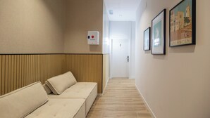 A hallway with a wooden panel wall, a reception desk, and framed pictures on the wall. - Rubio Rooms by Concept Flats (València)